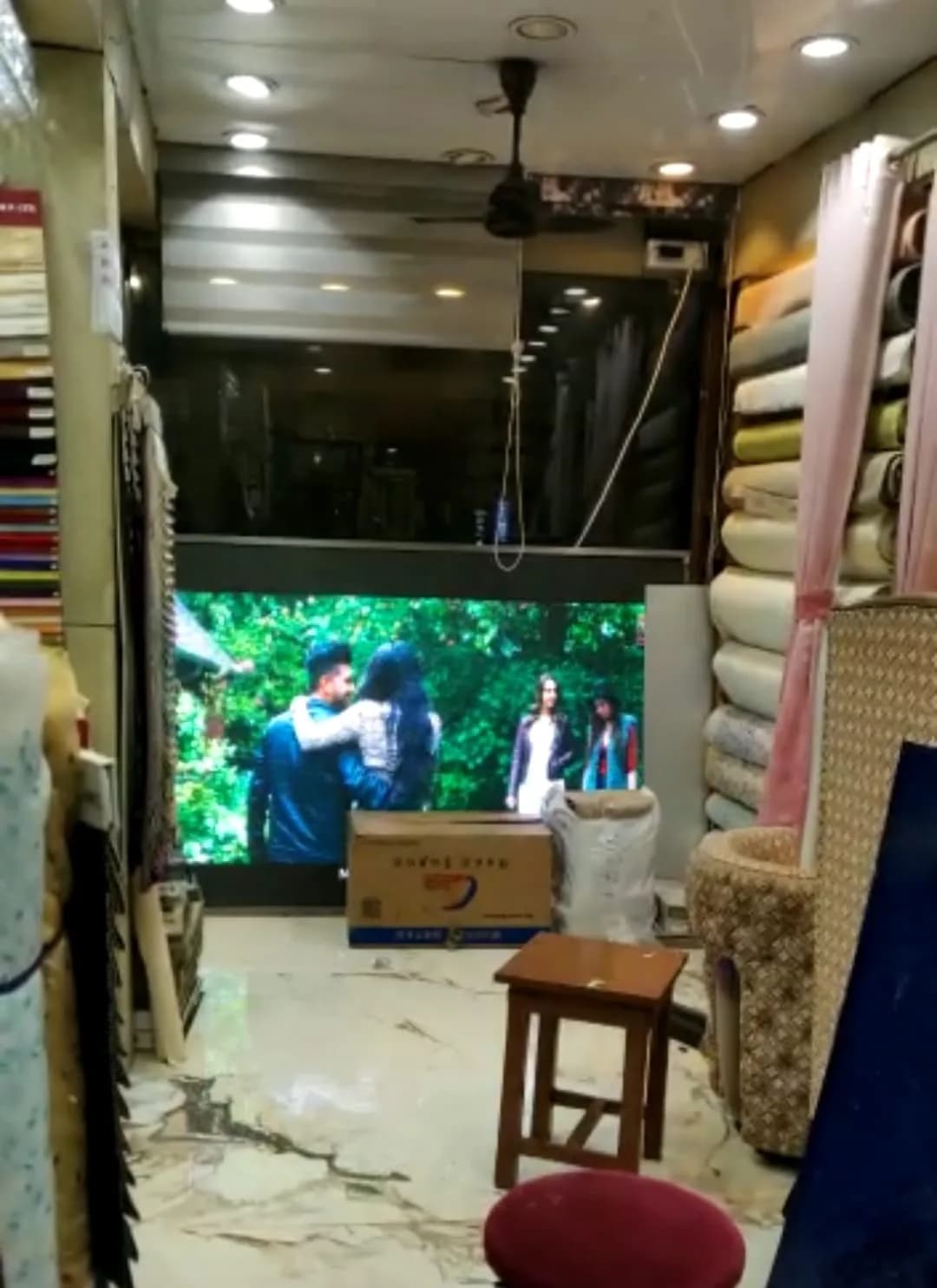 Indoor LED screen in a fabric shop showing a video of people in a garden